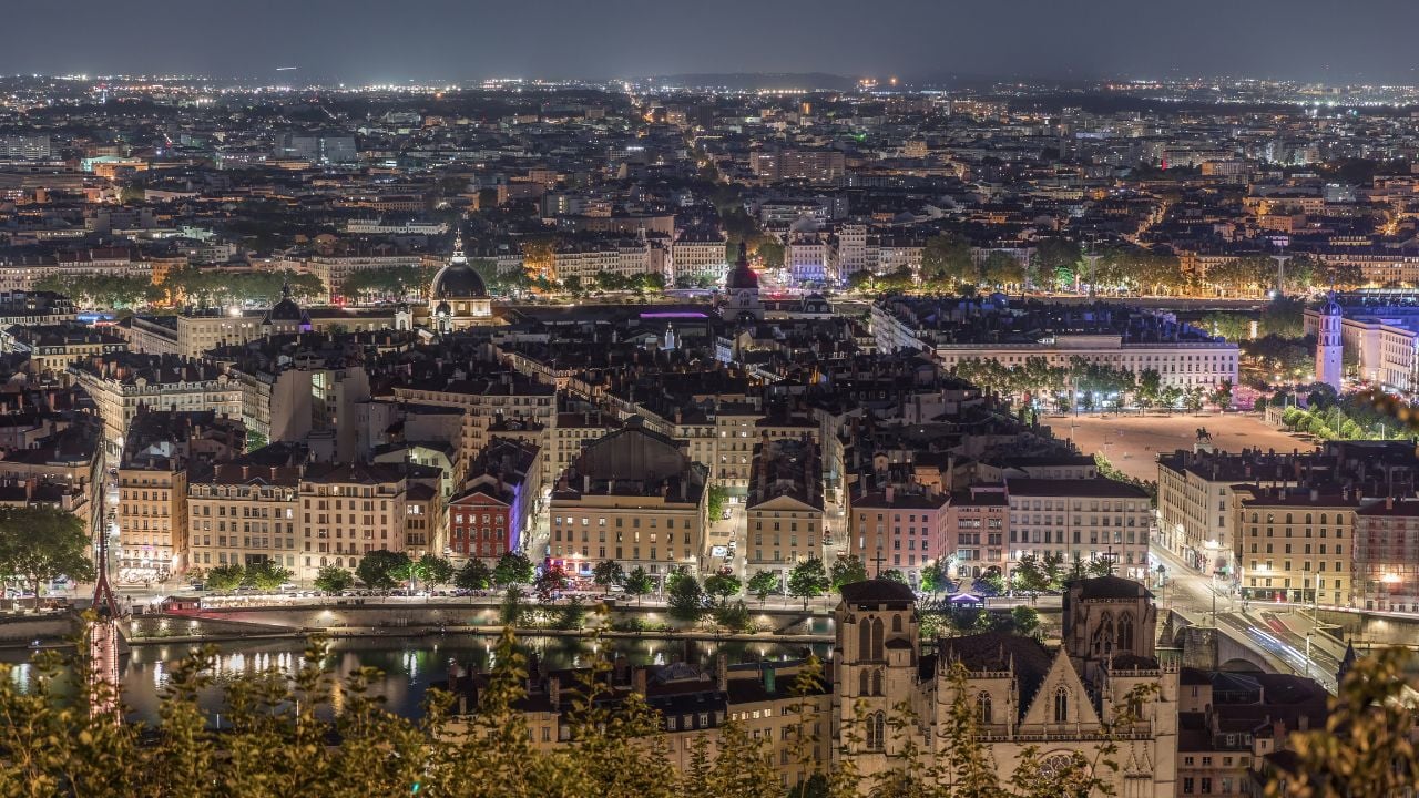 Lyon, France - Jul 25, 2024: Panoramic aerial view cathedrals from Fourviere Hill night. skyline features Rhone River iconic city landmarks illuminated at evening. Houses rooftops traffic on streets.