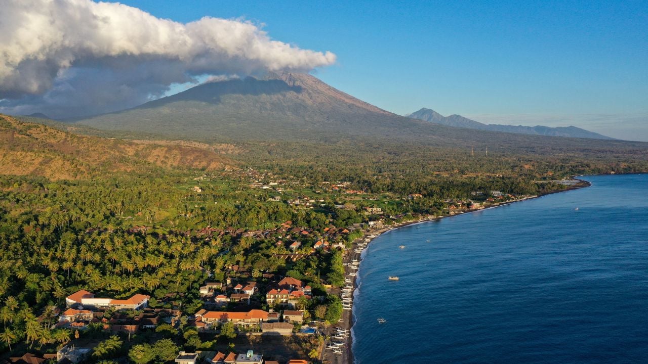 Amed coastline with Mount Agung, black sand beach, and traditional Balinese village.
