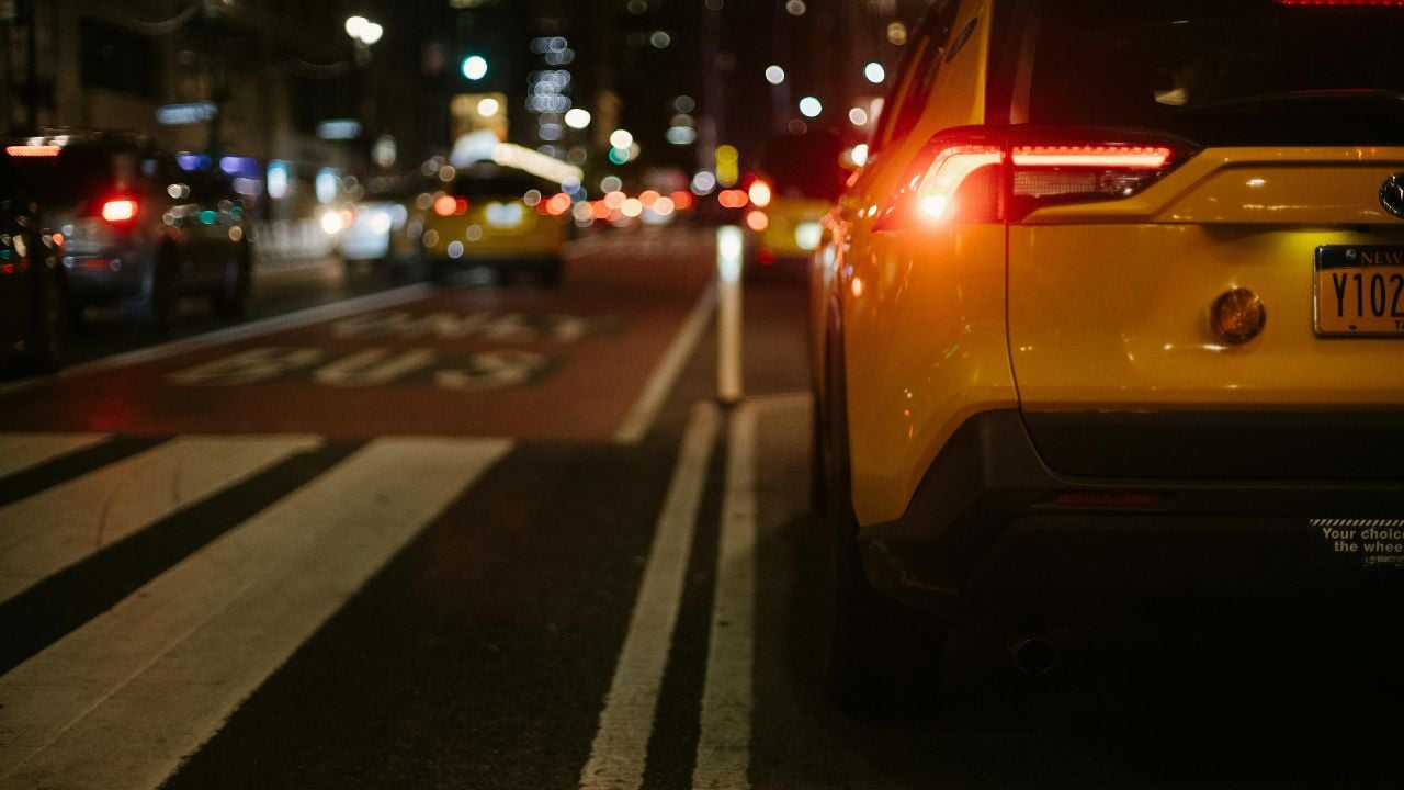 A yellow taxi navigates the busy city street at night, capturing urban nightlife