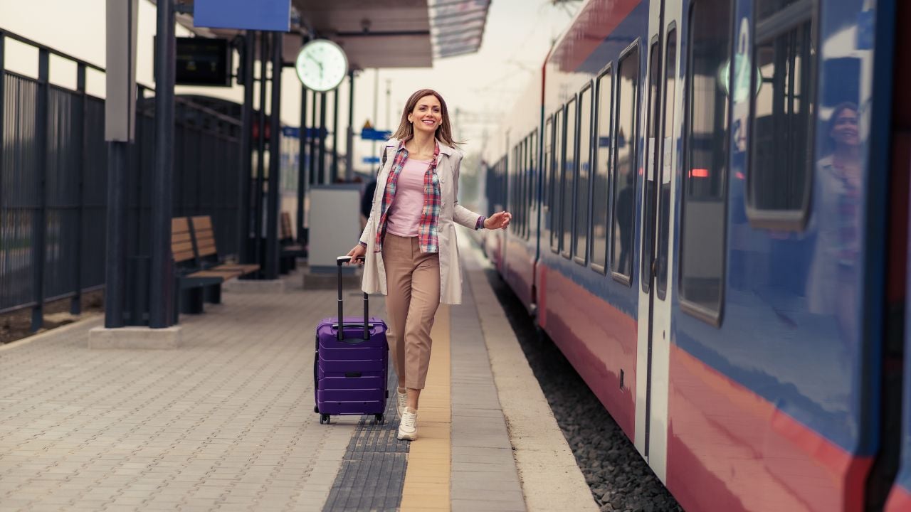 Woman with a suitcase running to catch a train at a station.