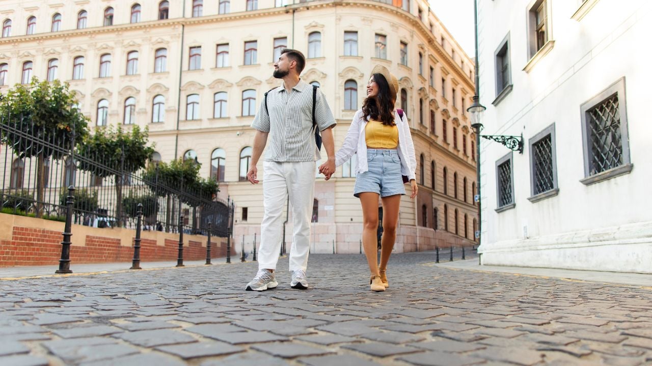 Happy tourists walking down a cobblestone street in a European city.