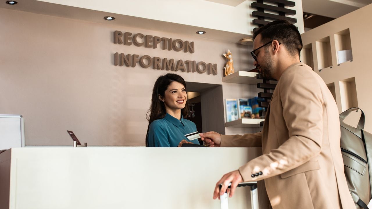 Hotel guest paying at reception with a credit card.