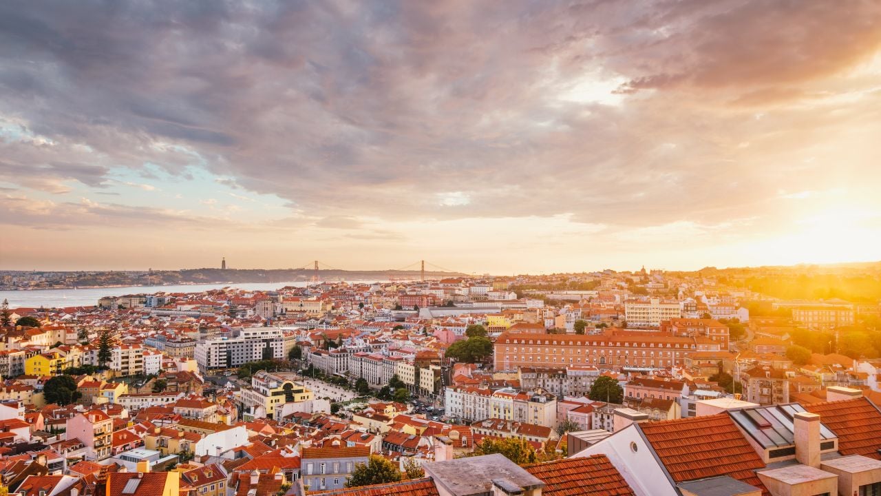 View of Lisbon famous view from Miradouro da Senhora do Monte tourist viewpoint of Alfama and Mauraria old city district, 25th of April Bridge at sunset. Lisbon, Portugal
