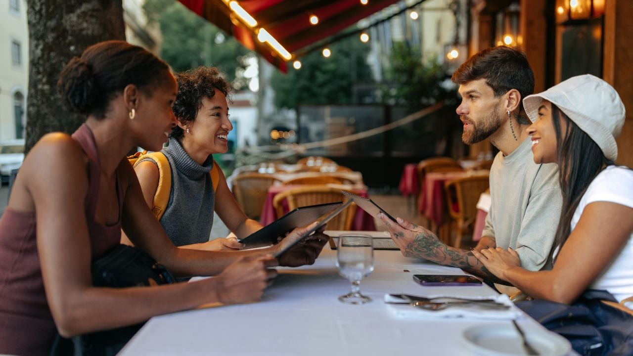 Group of tourists reading a menu at a restaurant table in Rome.
