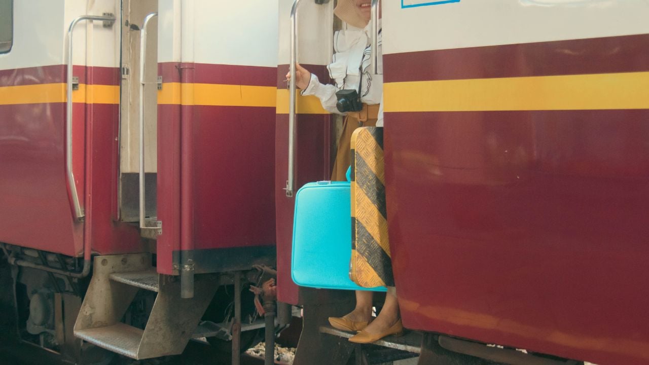 Traveler with luggage waiting for a train at a railway station.