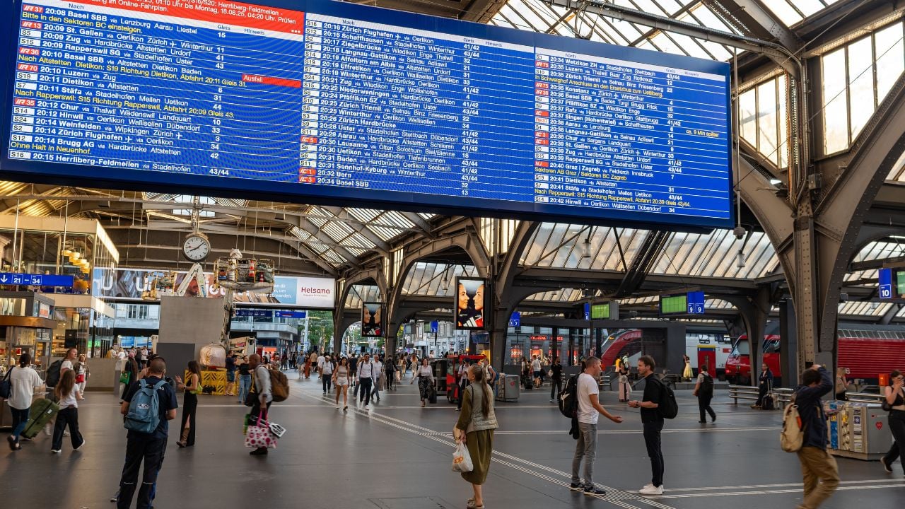 Travelers checking the departure board inside Zurich Hauptbahnhof.