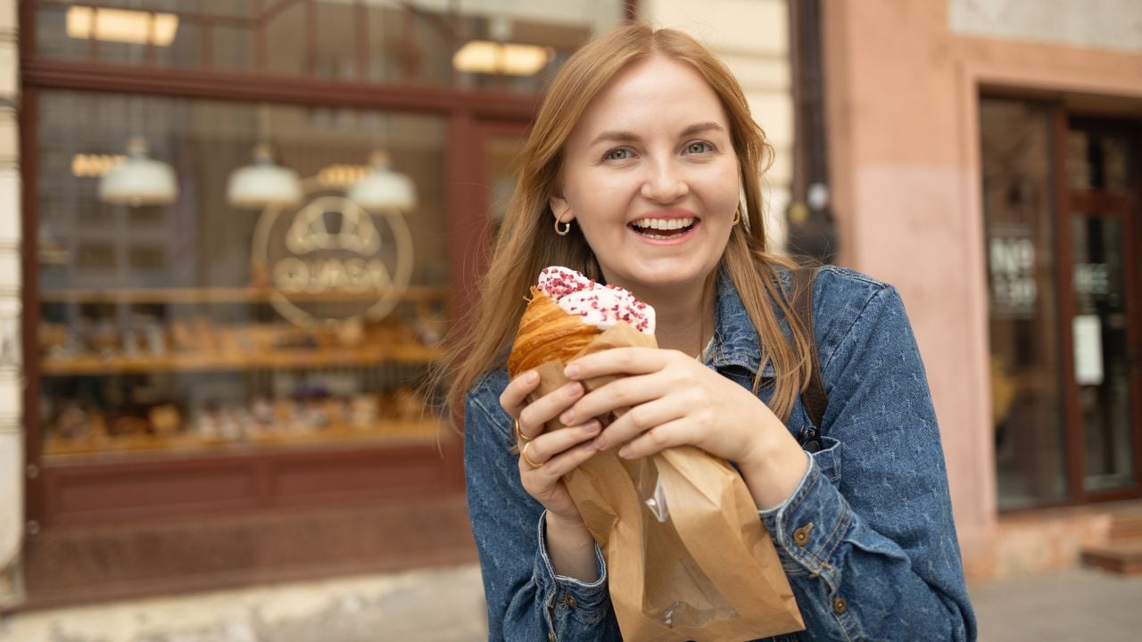 Woman enjoying breakfast with a croissant at an outdoor café.