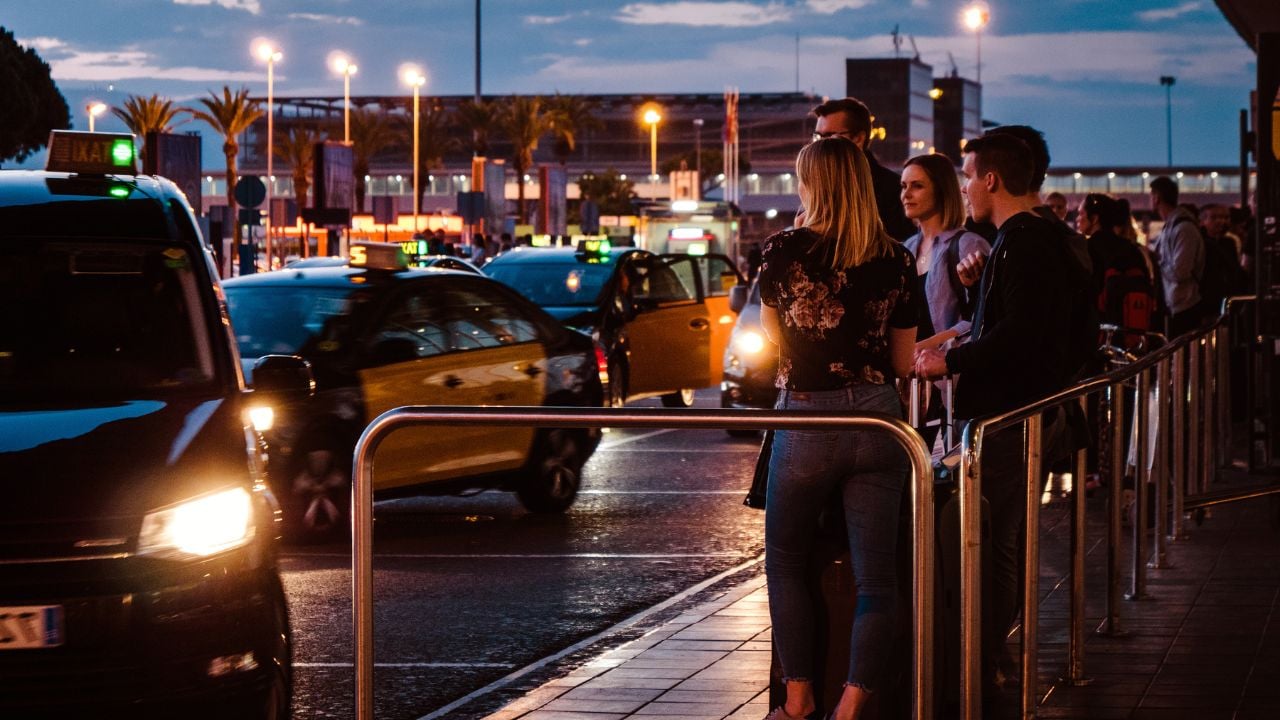Travelers waiting in a taxi queue outside Barcelona El Prat Airport.