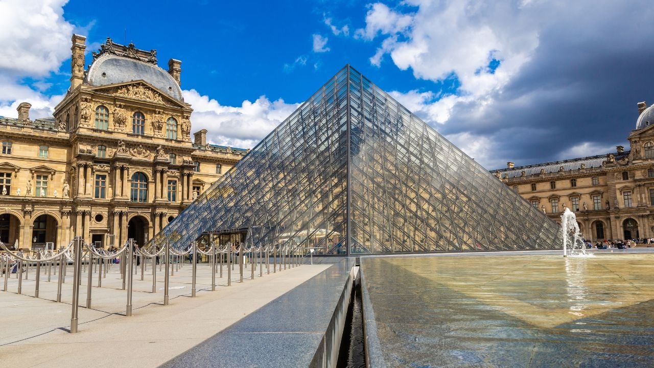 PARIS, FRANCE - JUNE 01, 2022: The Louvre and Pyramid - is one of the world's largest museums in Paris in a summer day, France
