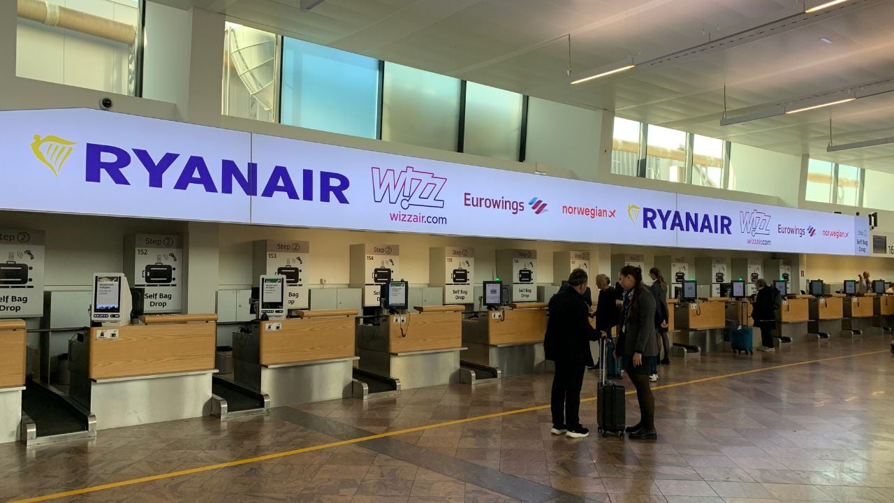 Passengers checking baggage at Vienna International Airport counters for low-cost carriers.
