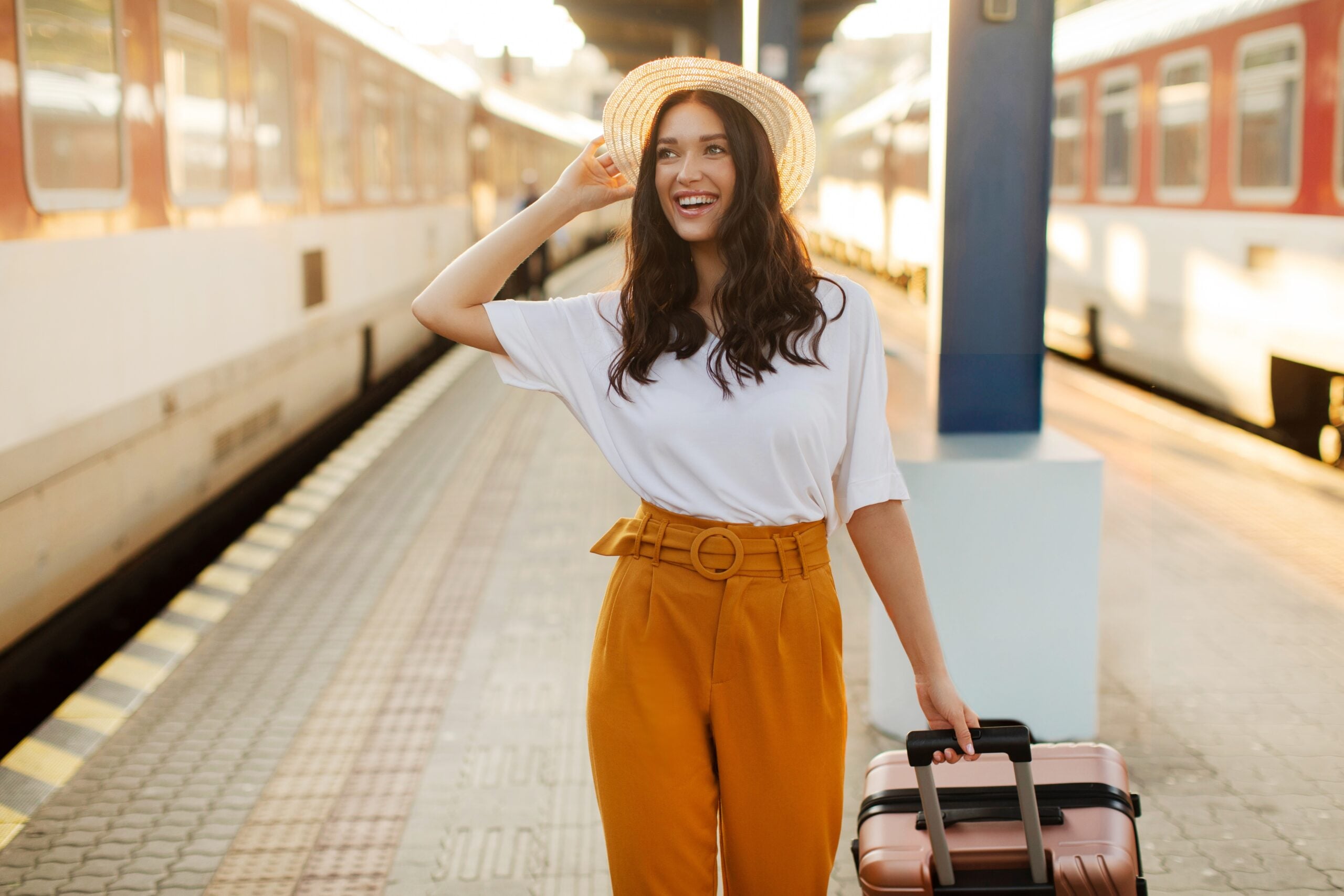 Smiling traveler with suitcase standing on a European railway station platform.