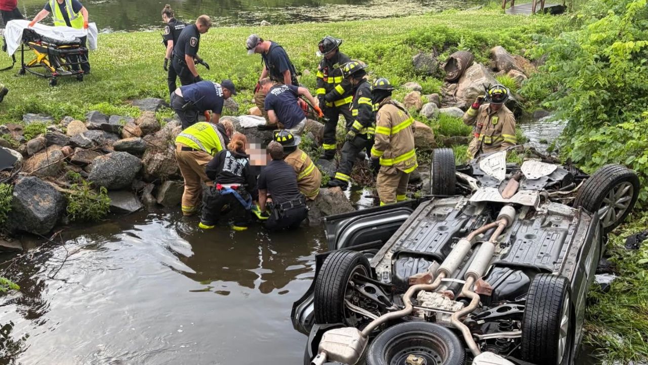 First responders rescue a driver from an overturned car in a river after a crash in Bethel, Connecticut.