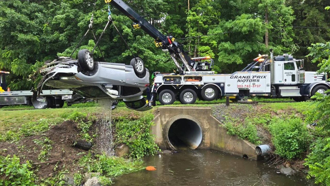 Heavy-duty crane lifts an overturned car from a river after a crash in Bethel, Connecticut.