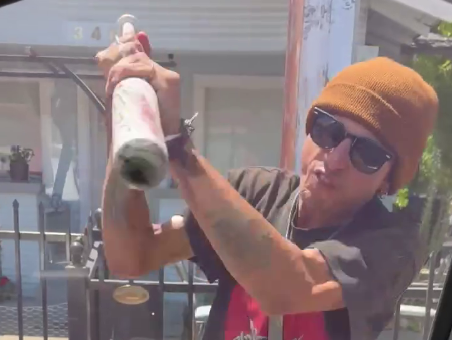 man breaking windows of cars