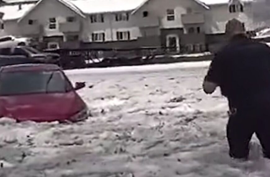Aurora Police Department Officer Wades through icy floodwater to get to woman stranded in maroon sedan