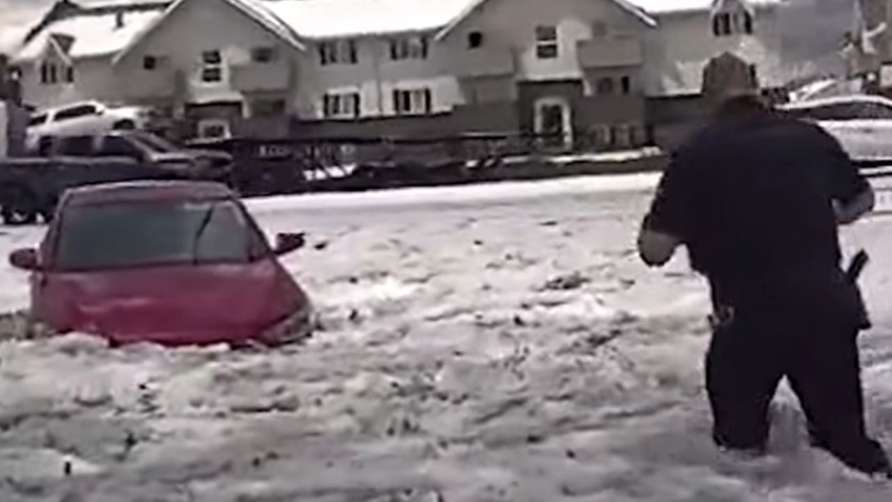 Aurora Police Department Officer Wades through icy floodwater to get to woman stranded in maroon sedan