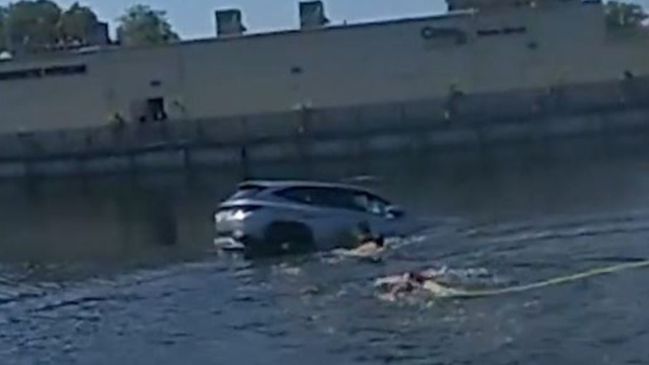 Broward Sheriff's Office deputies swimming towards a sinking car to rescue a woman