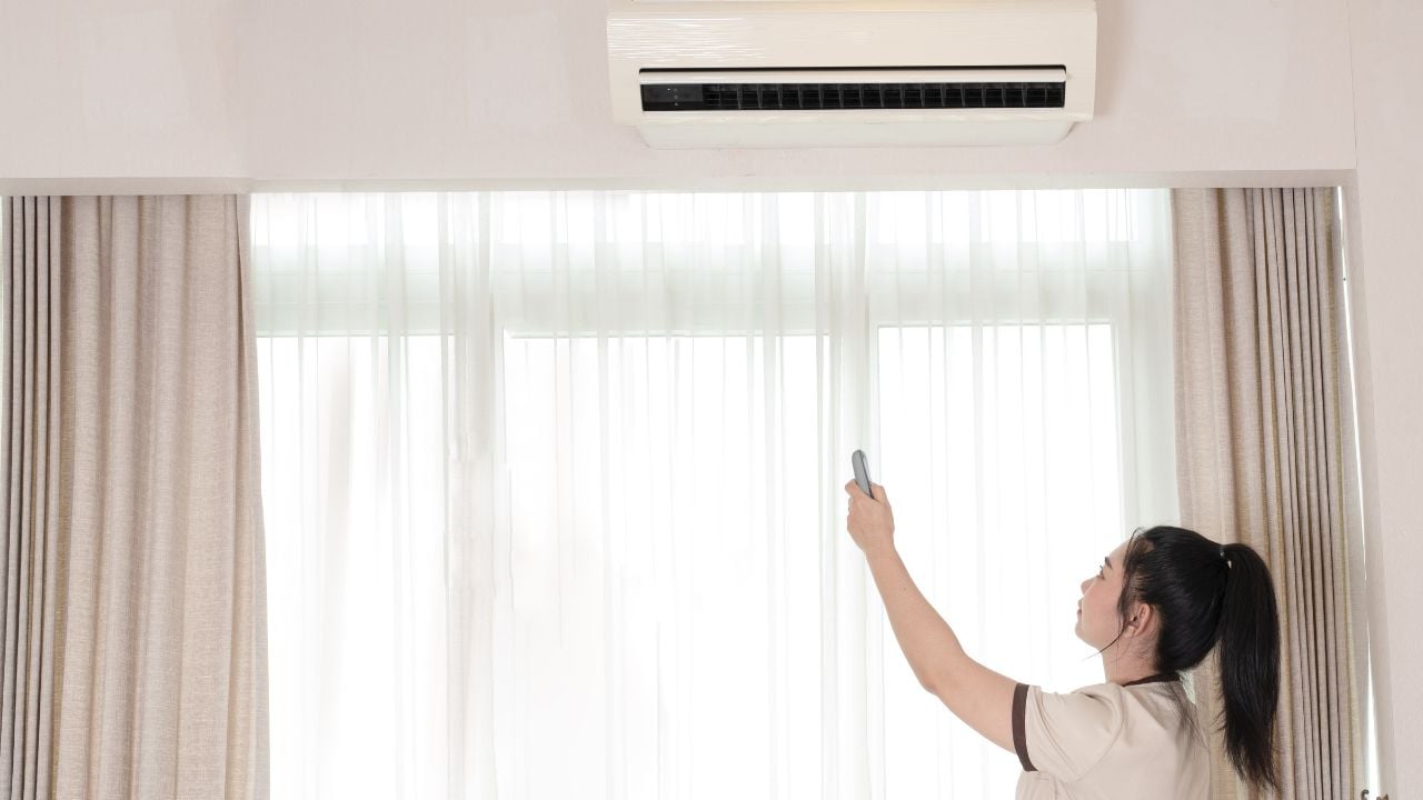 Hotel worker holding an air-conditioning remote in a guest room.