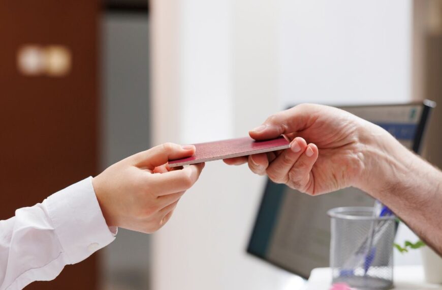 Close-up shot of caucasian pair of hands grasping passport for check-in verification procedure. In hotel reception, senior man handing his personal document to concierge for reservation.
