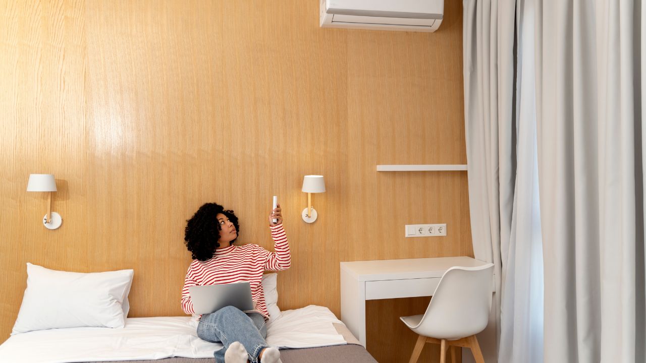 Hotel guest using air conditioner remote in a hotel room.