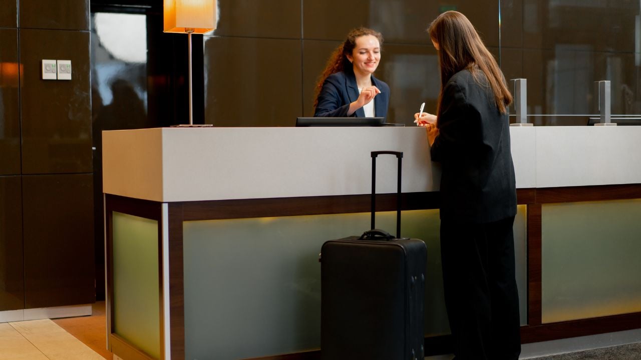 The receptionist at the counter meets the guest with luggage in hotel business travel hospitality