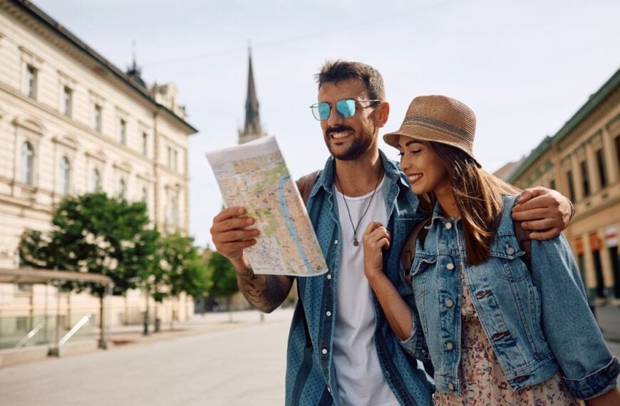 Happy couple of tourists reading map while walking through the city. Copy space.