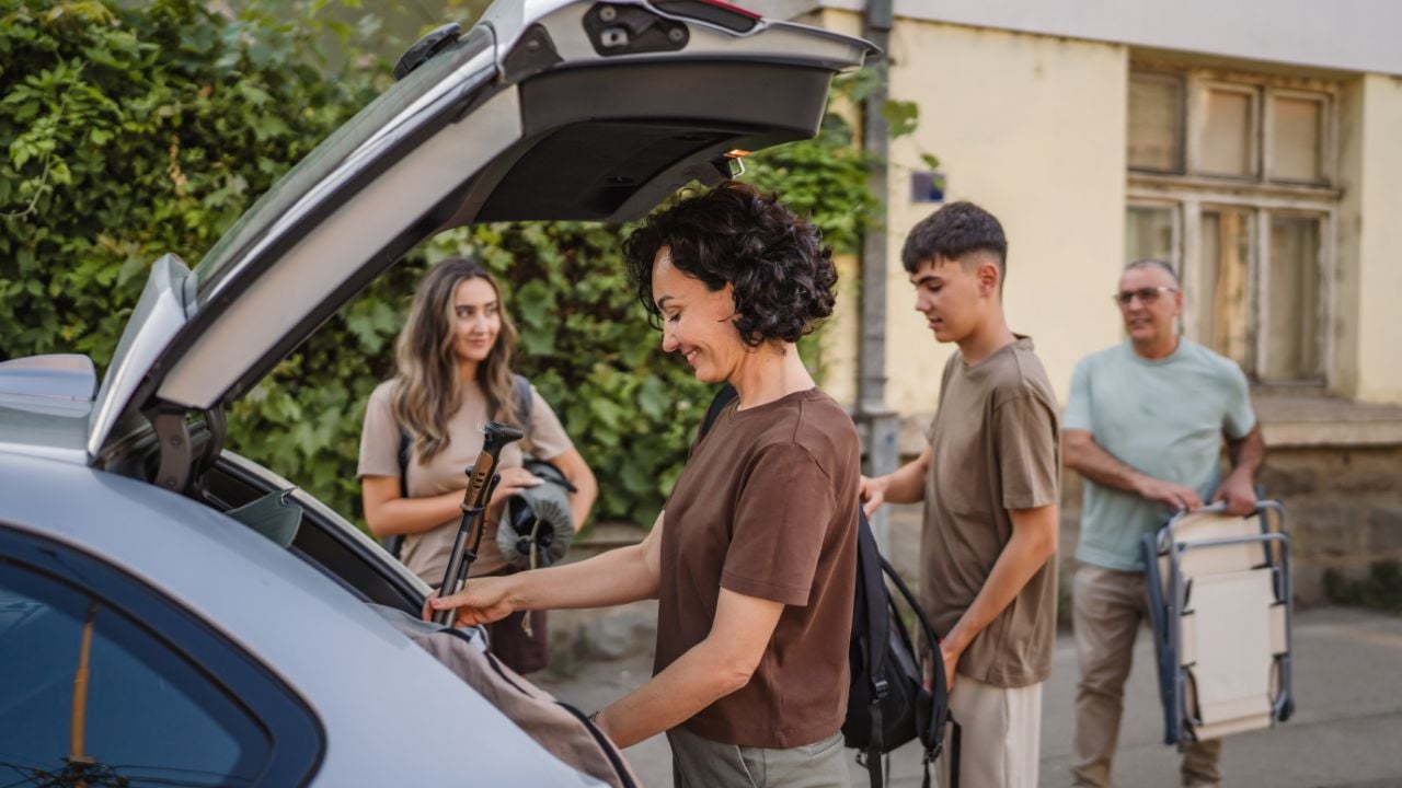 Family loading luggage and hiking gear into a car trunk before a trip