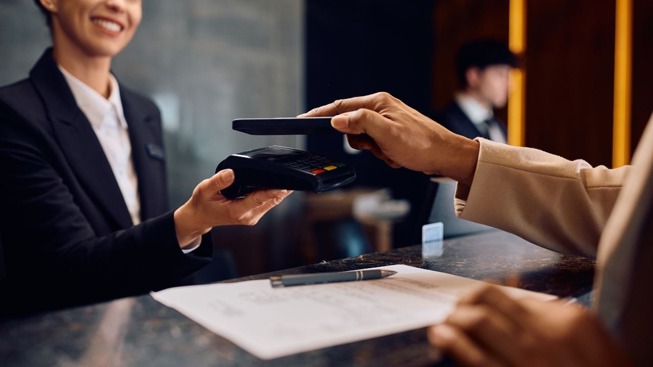 Hotel guest paying by phone at a reception desk