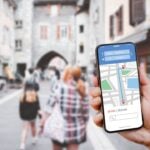 Hand holding Smartphone with Tourists using GPS map navigation apps on smartphone, blurred road background close up concept of online navigation and GPS, App online with travel and technology.