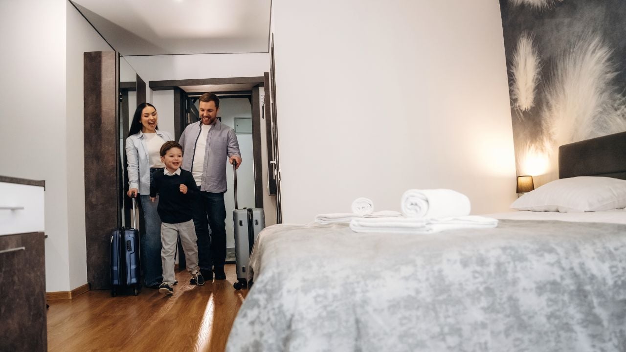 Family entering a hotel room with luggage