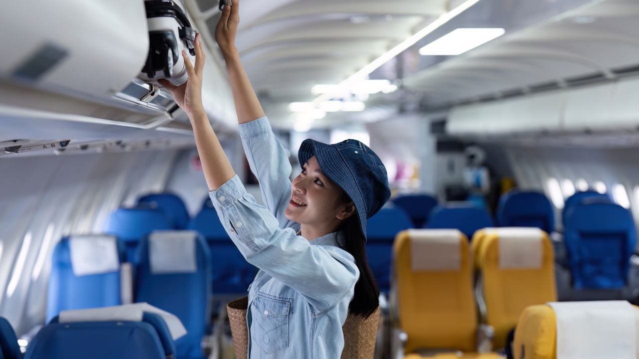 Passenger placing a bag in the overhead compartment on an airplane