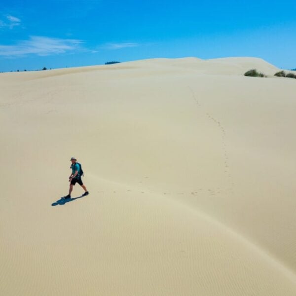 a hiker walking across the dunes in oregon