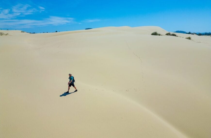 a hiker walking across the dunes in oregon