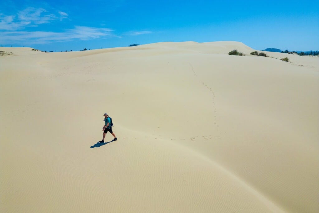 a hiker walking across the dunes in oregon