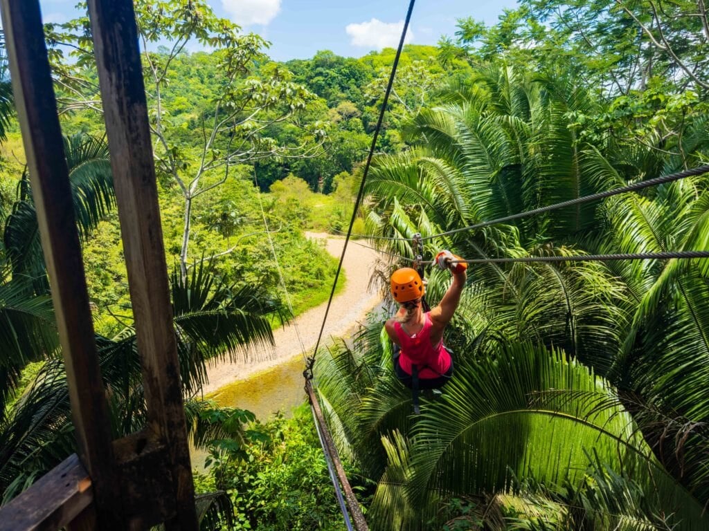 a woman ziplines through the belize jungle