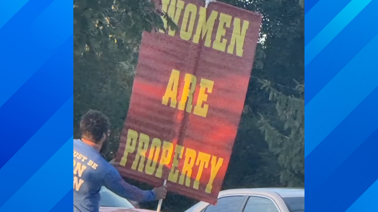 man holds up sexist sign outside of school