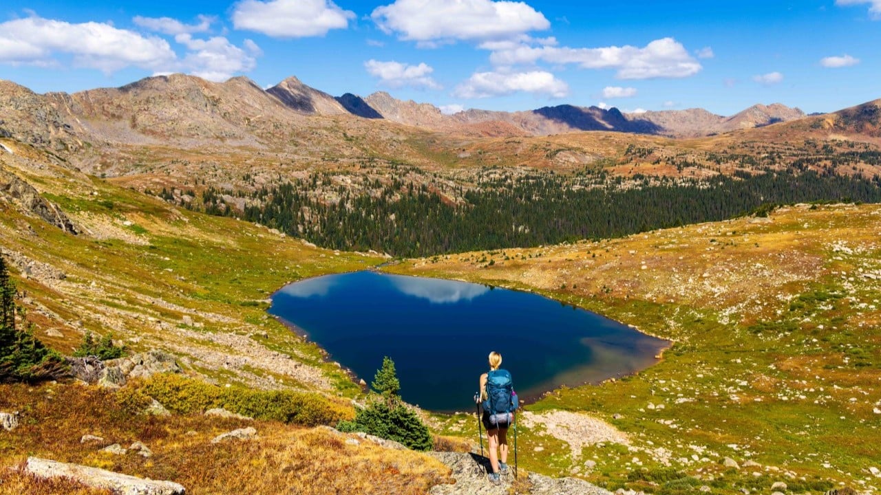 a hiker looks out at a lake in colorado