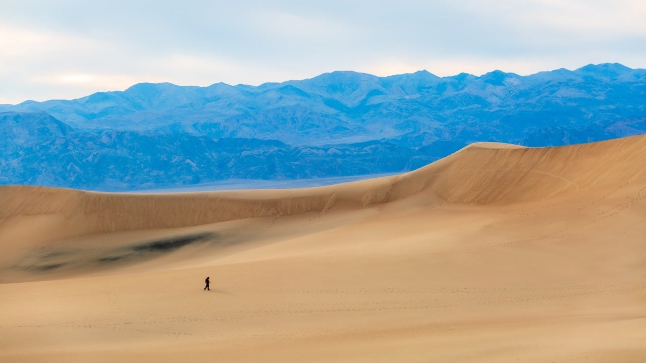 a person walks on sand dunes in death valley