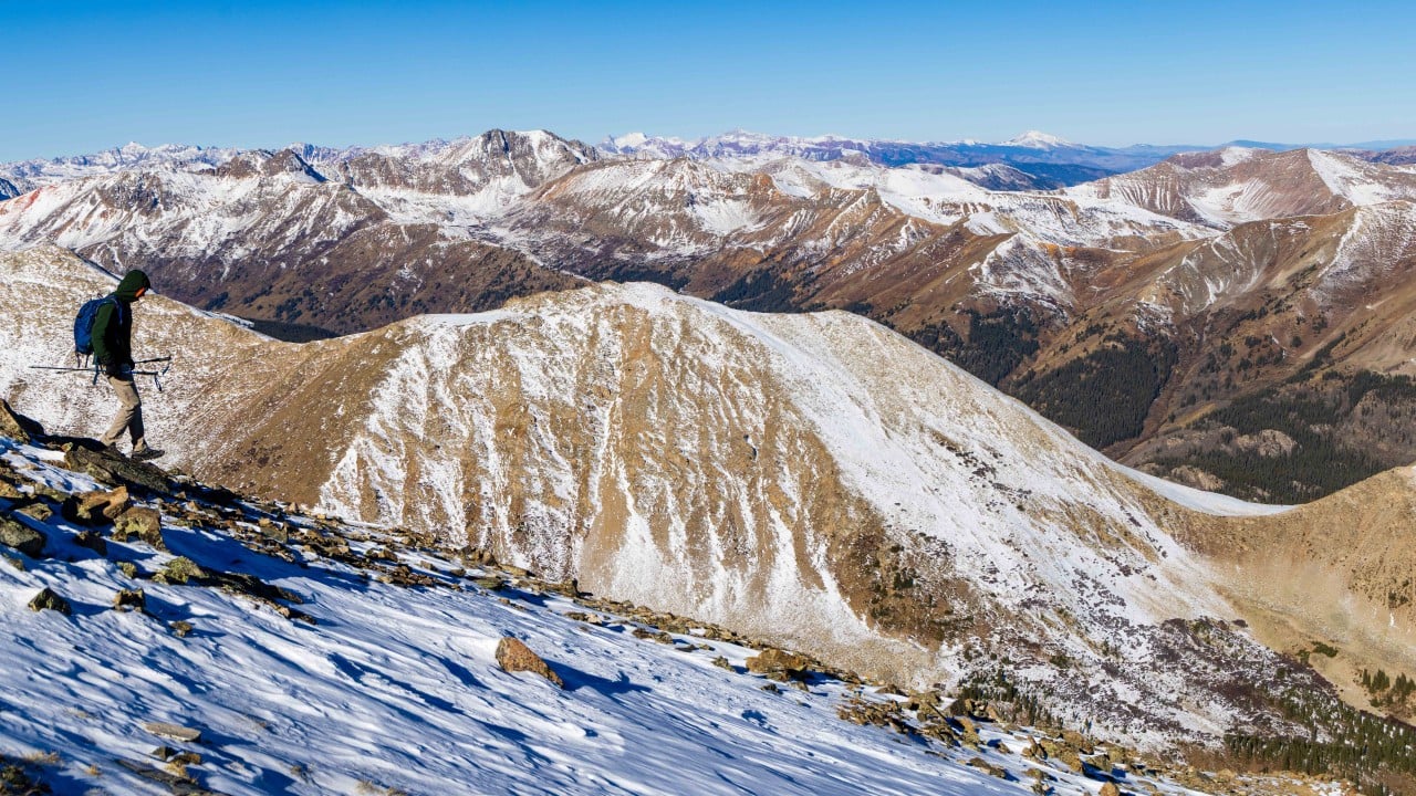 a hiker walking down a snowy slope