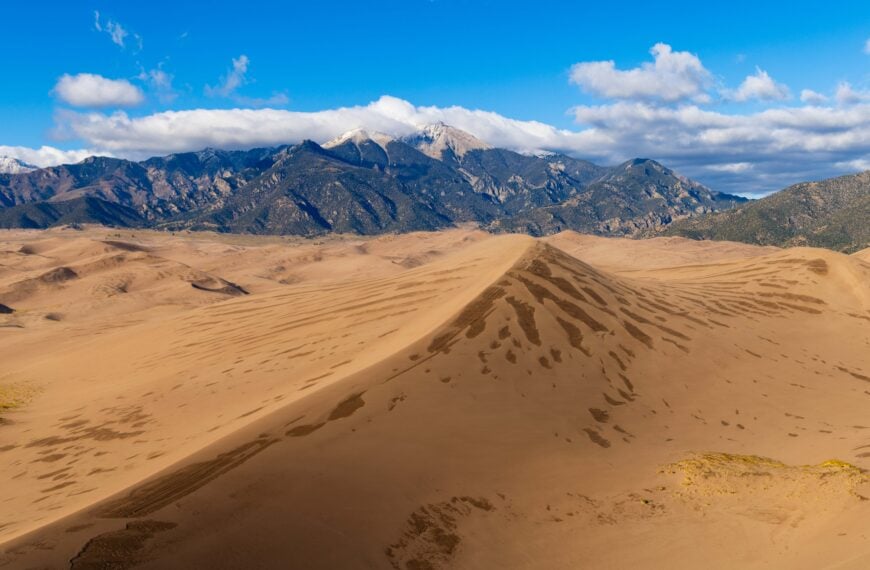 sand dunes in colorado with mountains in the background